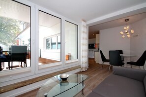 A modern living room with a glass coffee table, a sofa, and a dining area with chairs.