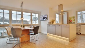 Una cocina moderna con una isla central, ventanas amplias y un comedor con sillas.