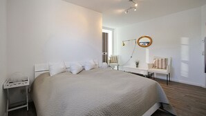 Un dormitorio moderno con una cama grande, mesitas de noche, un escritorio y un espejo.