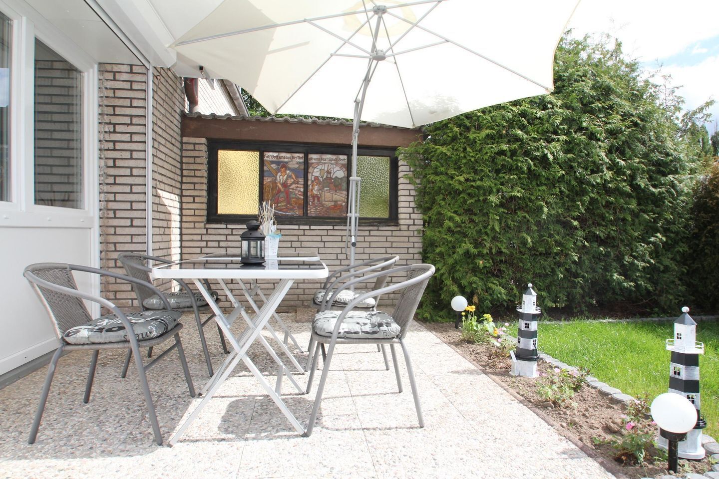 A patio with a table and chairs, a lantern, and decorative garden elements.