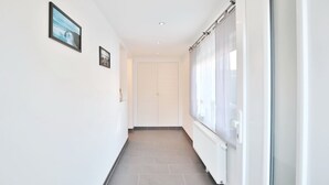 A hallway with a tiled floor, white walls, and a door at the end.