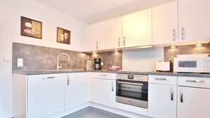 A modern kitchen with white cabinets, a built-in oven, a coffee maker, and a microwave.