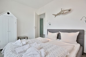 Un dormitorio con una cama, un armario y una decoración de tiburón en la pared.