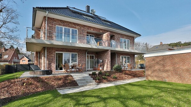 A two-story house with a brick exterior, large windows, and a covered patio area. - Baltic Sea Apartment 1 - Baltic Sea (Timmendorfer Strand)