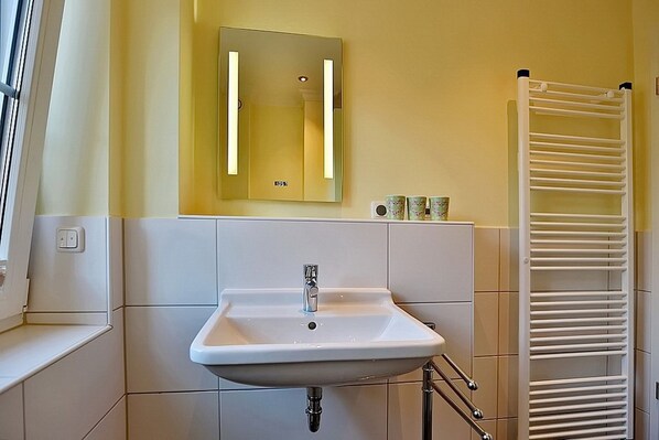 Une salle de bain avec un lavabo blanc, un miroir et un porte-serviettes.