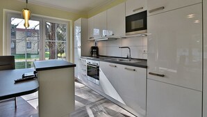 Una cucina moderna con mobili bianchi, un piano di lavoro nero e un forno integrato.