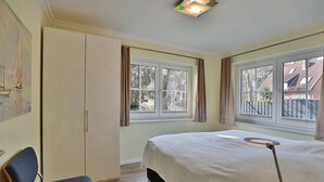 Una camera da letto con un letto, una sedia, un armadio e finestre con tende.