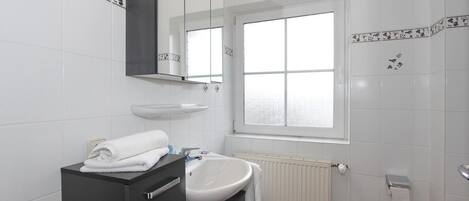 A modern bathroom with a white sink, dark vanity, and a large mirror.