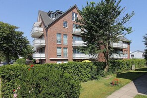 A multi-story residential building with balconies, surrounded by well-maintained hedges and a clear sky. - Residenz Alte Bergstrasse Apartment 21 - Residenz Alte Bergstrasse (Scharbeutz)