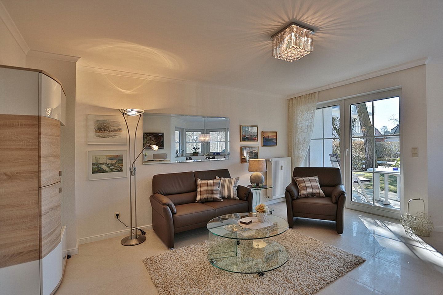 A modern living room with two sofas, a glass coffee table, and a chandelier.