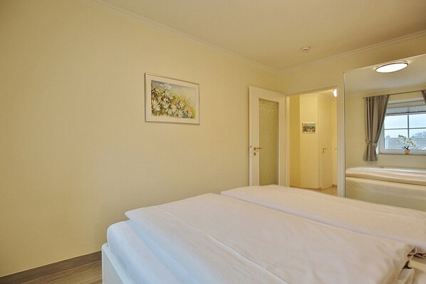 Una habitación de hotel con dos camas, una puerta que da a un baño y una ventana con cortinas.