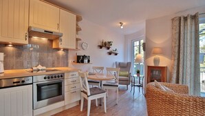 A modern kitchen with white cabinets, a dining area with a table and chairs, and a cozy seating area with a sofa.