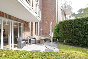 A patio with outdoor furniture, a glass door entrance, and a brick wall.