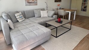 Una sala de estar moderna con un sofá seccional gris, una mesa de centro y un comedor con una mesa de madera y sillas.