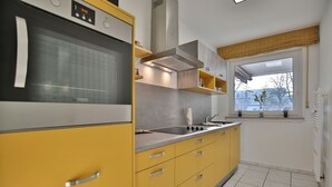 Una cocina con armarios amarillos, horno empotrado, estufa y ventana con vistas.