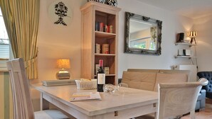 Ein Essbereich mit Tisch, Stühlen, einer Weinflasche und einem Korb.