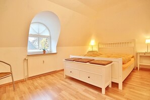 A bedroom with a bed, bedside tables, a window with a view, and a radiator. - Residenz Weedkroog Appartement 9 - Residenz Weedkroog (Timmendorfer Strand)