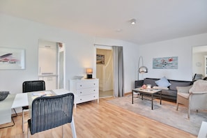 A modern living room with a dining area, a sofa, a coffee table, and a TV. - Residenz Weedkroog Appartement 9 - Residenz Weedkroog (Timmendorfer Strand)