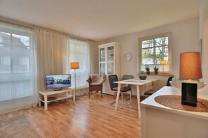 A modern living room with a television, dining table, chairs, and a cabinet. - Residenz Weedkroog Appartement 9 - Residenz Weedkroog (Timmendorfer Strand)