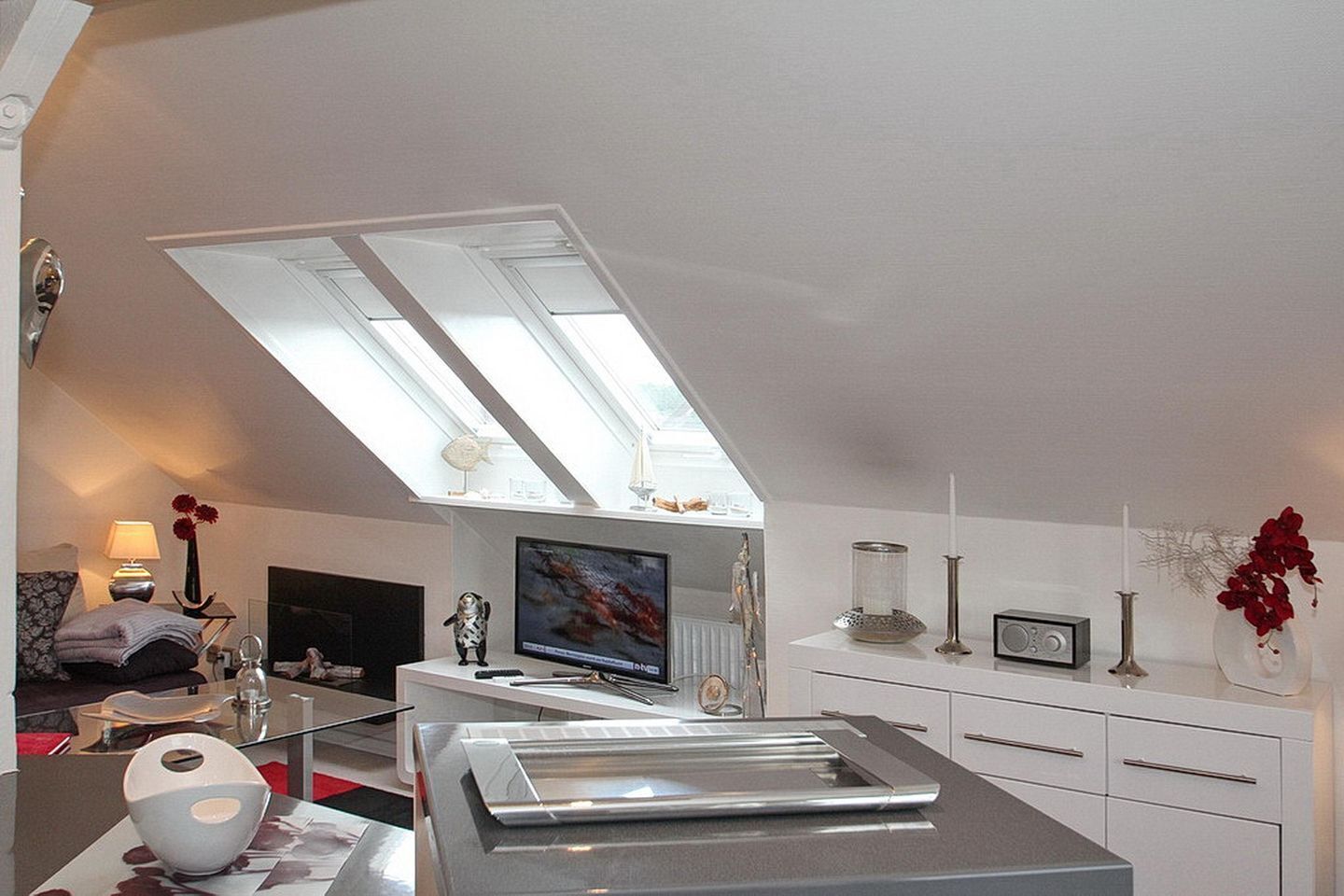 Eine moderne Küche mit Oberlicht, einem Flachbildfernseher und einem Essbereich mit Tisch und Stühlen.