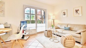 A modern living room with a sofa, a dining table, and a TV.