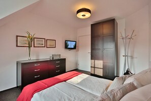 A bedroom with a bed, a dresser, a television, and a wardrobe.