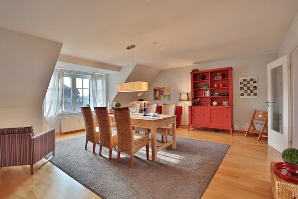 A dining area with a table and chairs, a red cabinet, and a window with curtains.