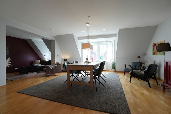 A modern loft apartment with a dining area, a living space, and a bedroom.