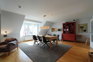 A modern living space with a dining area, a red cabinet, and a large window.