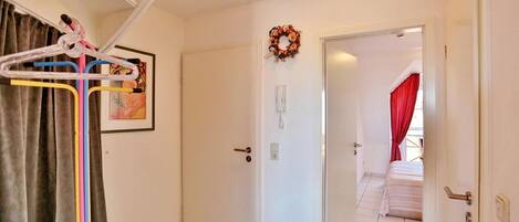 Habitación de hotel con una puerta blanca, un cuadro enmarcado, un teléfono y una cortina roja.