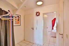 A hotel room with a white door, a framed picture, a telephone, and a red curtain.