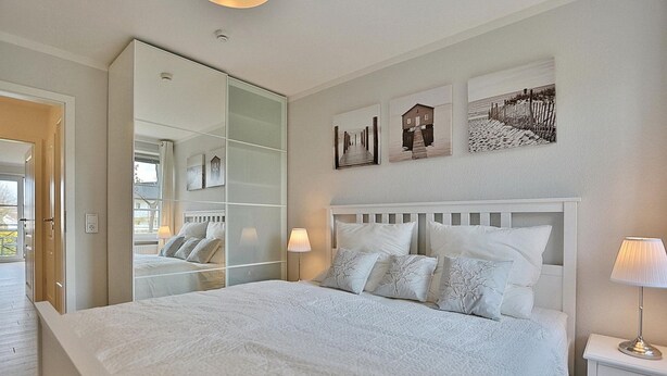 A bedroom with a large bed, a mirror, and artwork on the wall.