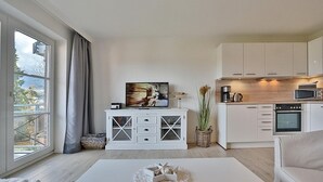 A modern apartment with a living room, kitchen, and a large window.