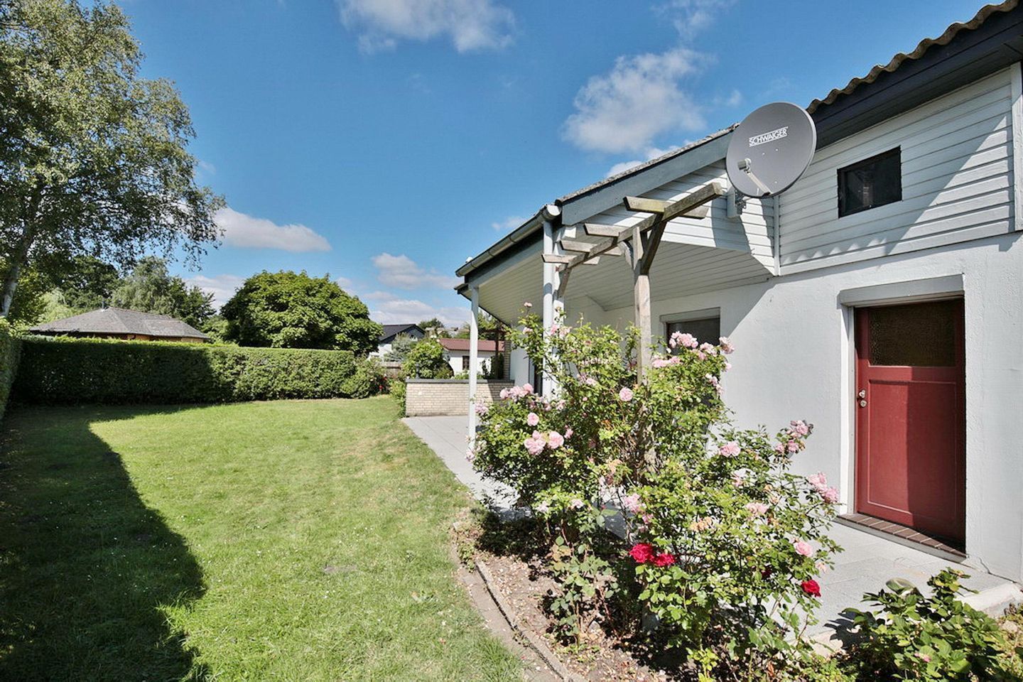 A residential property with a well-maintained lawn, a satellite dish, and a red door.