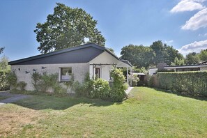 A single-story house with a sloped roof, a small porch, and a well-maintained garden.
