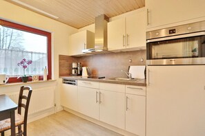 A modern kitchen with white cabinets, a stainless steel oven, and a coffee maker on the counter.