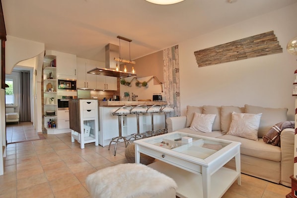 Une cuisine moderne avec des meubles blancs, un îlot central doté de tabourets et un luminaire suspendu.