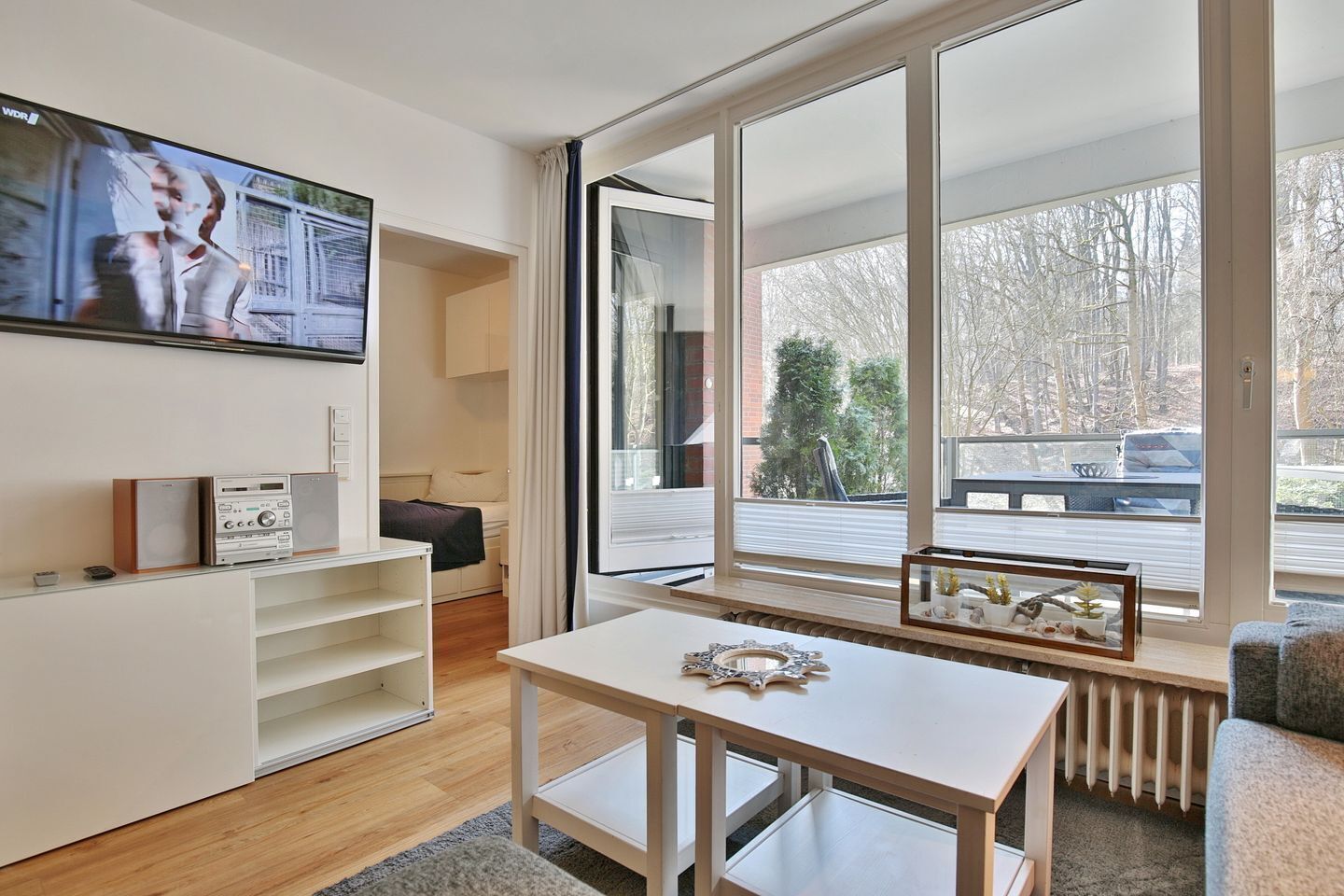 A modern living room with a large TV, a wooden table, and a sofa.