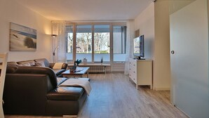 A modern living room with a leather sofa, a coffee table, and a TV on a stand.