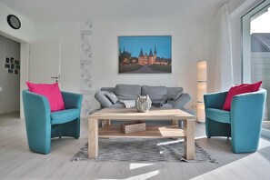 Uma sala de estar moderna com um sofá, uma mesa de centro e uma janela grande com vista para um edifício histórico.