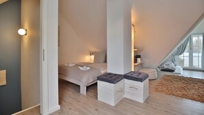 Ein Schlafzimmer mit schrägen Wänden, einem Bett, Nachttischen und einem Fenster mit Blick.