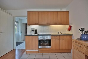 Una cocina compacta con armarios de madera, horno integrado y cafetera.