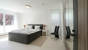 A modern bedroom with a large bed, bedside tables, a chair, and a large mirror.