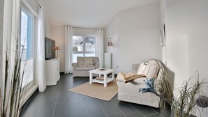 A modern living room with a sofa, a coffee table, and a TV. - Penthouse am Platz Apartment 10 - Penthouse am Platz (Timmendorfer Strand)