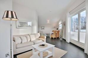 A modern living room with a sofa, coffee table, and dining area.