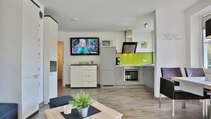 A modern kitchen with a TV, cabinets, and a dining area with chairs.