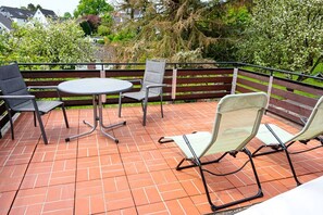 Un patio con una mesa redonda y cuatro sillas, rodeado de piso de ladrillo y cerca de madera.