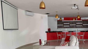 A modern living room with a white sofa, a coffee table, and a red dining area with chairs. - Beautiful apartment with jacuzzi in Diamante Lakes (Acapulco de Juárez)