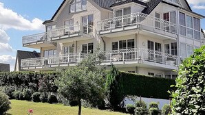 Un immeuble à plusieurs étages doté de balcons, de grandes fenêtres et d’un espace jardin.
