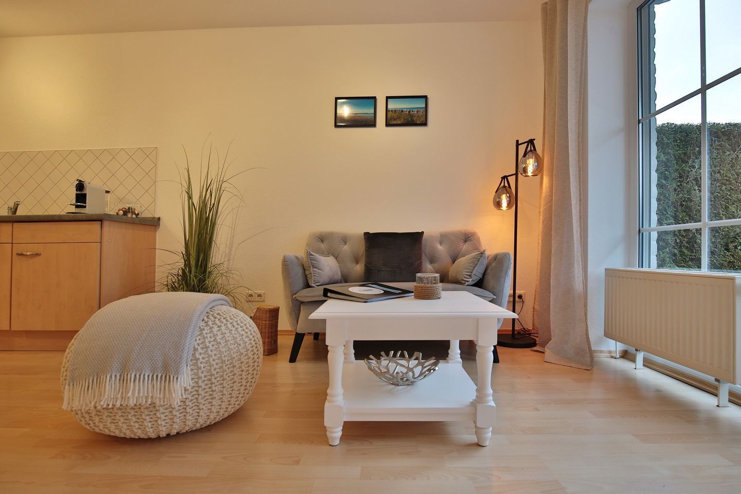 Un salon confortable avec un canapé, une table blanche et une grande fenêtre.